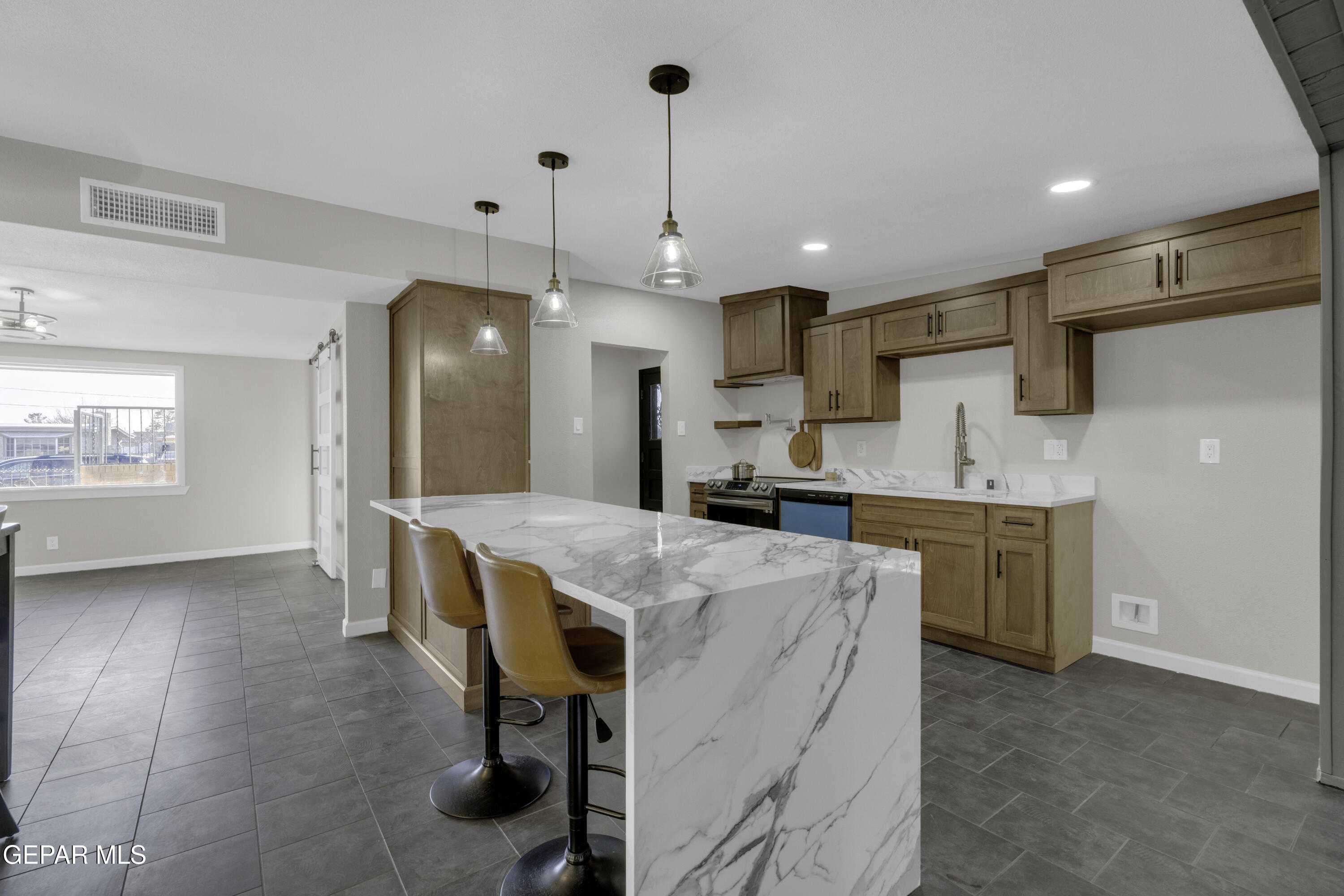 7125 Banana Tree Lane El Paso, TX 79915 - Photo 23 of 62 a kitchen with kitchen island a stove a refrigerator a sink a dining table and chairs with wooden floor