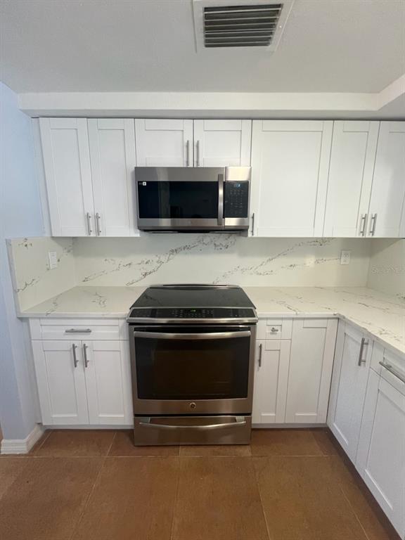 3631 Grayton Drive New Port Richey, FL 34652 - Photo 9 of 42 a kitchen with granite countertop white cabinets and stainless steel appliances