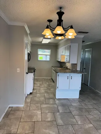 a kitchen with kitchen island granite countertop a stove a sink a counter top space and cabinets