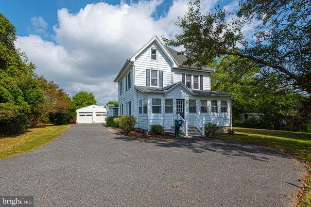 a front view of a house with a garden and trees