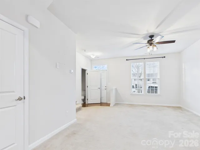 an empty room with a ceiling fan and windows