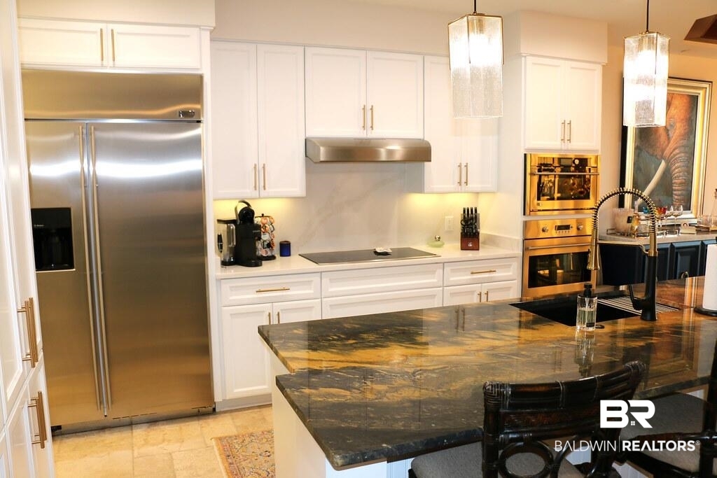 18269 Colony Drive, Unit 803 Fairhope, AL 36532 - Photo 3 of 27 Kitchen with stainless steel appliances, dark stone countertops, white cabinetry, and under cabinet range hood