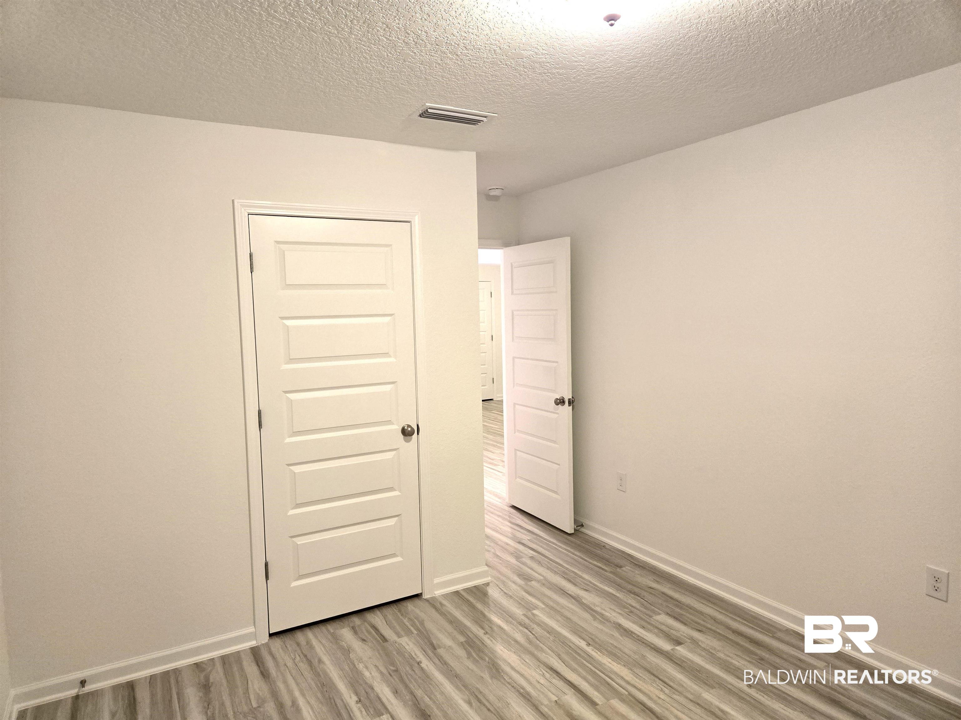 24385 Ringneck Loop Elberta, AL 36530 - Photo 23 of 33 Empty room with a textured ceiling and light hardwood / wood-style floors