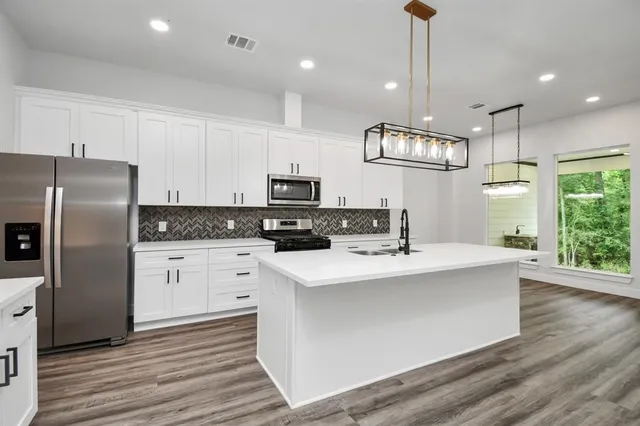 a kitchen with kitchen island white cabinets and stainless steel appliances