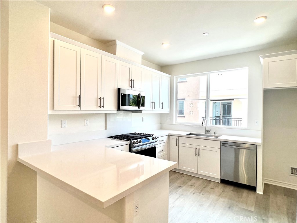a kitchen with stainless steel appliances a white cabinets wooden floor and a sink