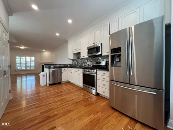 a kitchen with granite countertop stainless steel appliances a refrigerator cabinets and wooden floor