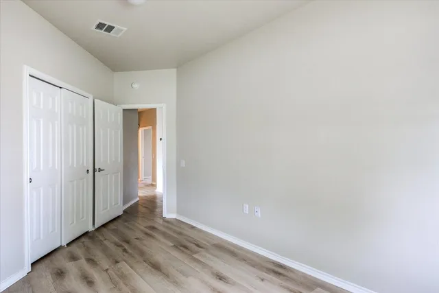an empty room with wooden floor and window