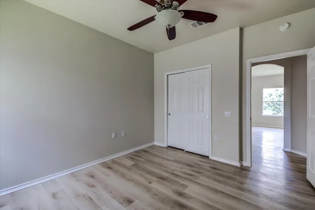 a view of empty room with wooden floor and fan