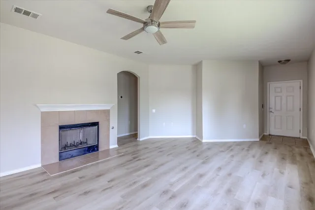 an empty room with wooden floor fireplace and windows