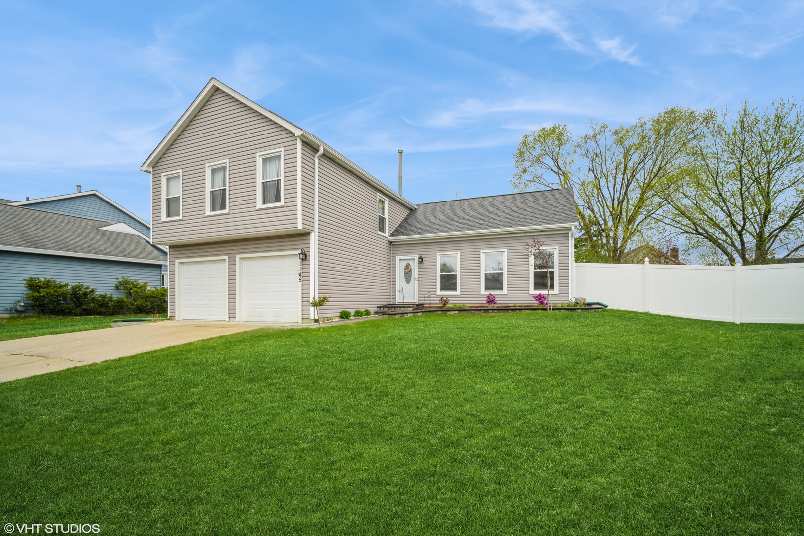 a view of a yard in front of a house with plants and large trees