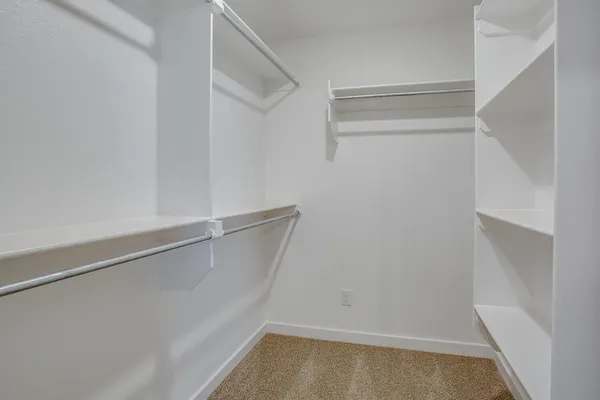 an empty room with chandelier fan and closet area