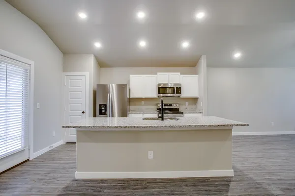 a kitchen with stainless steel appliances granite countertop a refrigerator a sink a stove a microwave and island