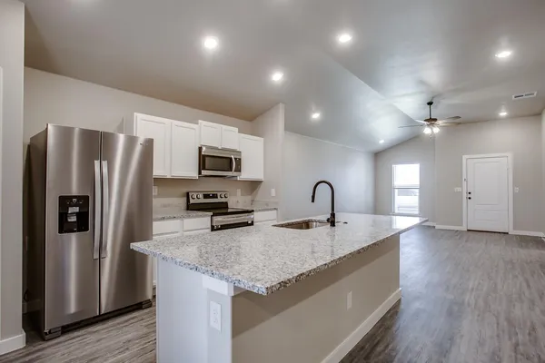 a kitchen with stainless steel appliances granite countertop a sink a oven a dining table and chairs