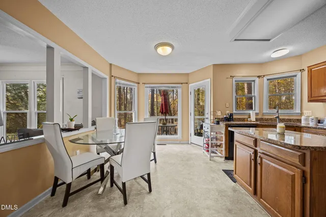 a kitchen with kitchen island granite countertop a stove top oven a sink dishwasher a dining table and chairs with wooden floor