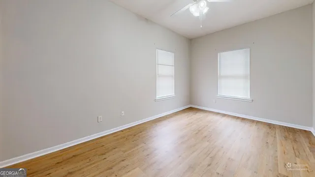 a view of empty room with wooden floor and fan