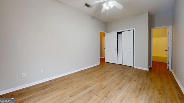 an empty room with wooden floor and a ceiling fan