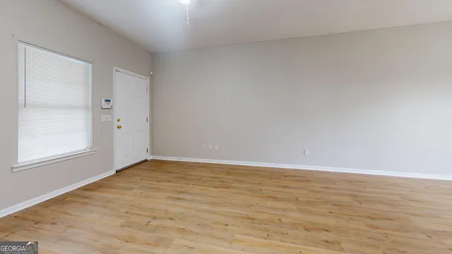 a view of an empty room with window and wooden floor