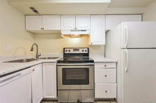 a kitchen with granite countertop white cabinets and white stove