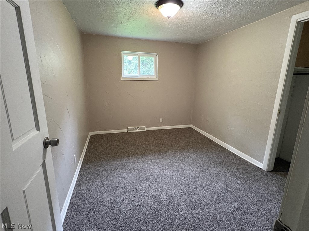 1448 Winding Road Parkersburg, WV 26104 - Photo 6 of 12 Room featuring light neutral painted walls, gray carpet flooring, white baseboards, a white-framed window, and a ceiling-mounted light fixture