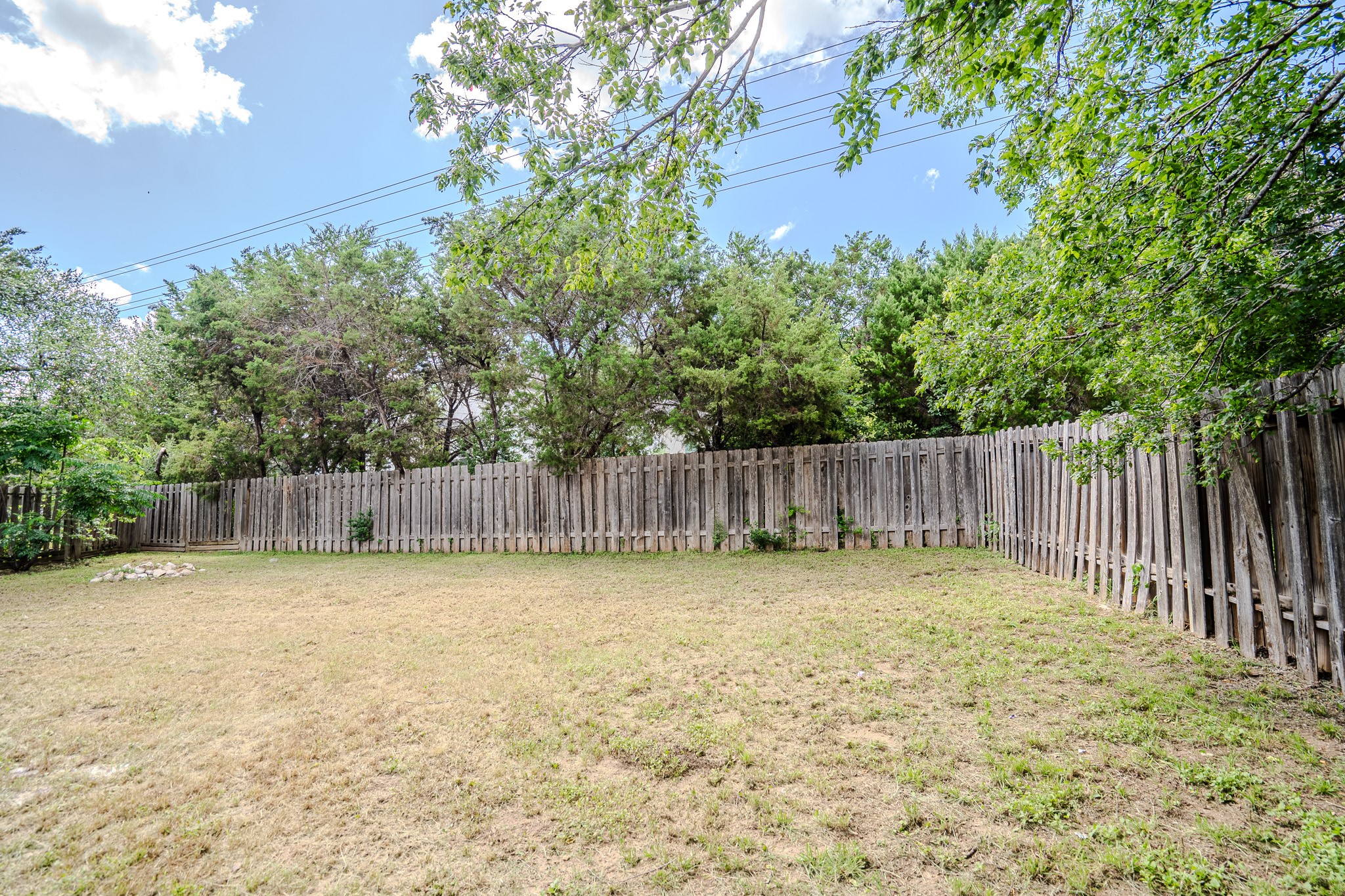 517 Cutty Trail, Unit B Lakeway, TX 78734 - Photo 14 of 16 A spacious yard enclosed by a wooden fence, offering a private outdoor area for recreation.