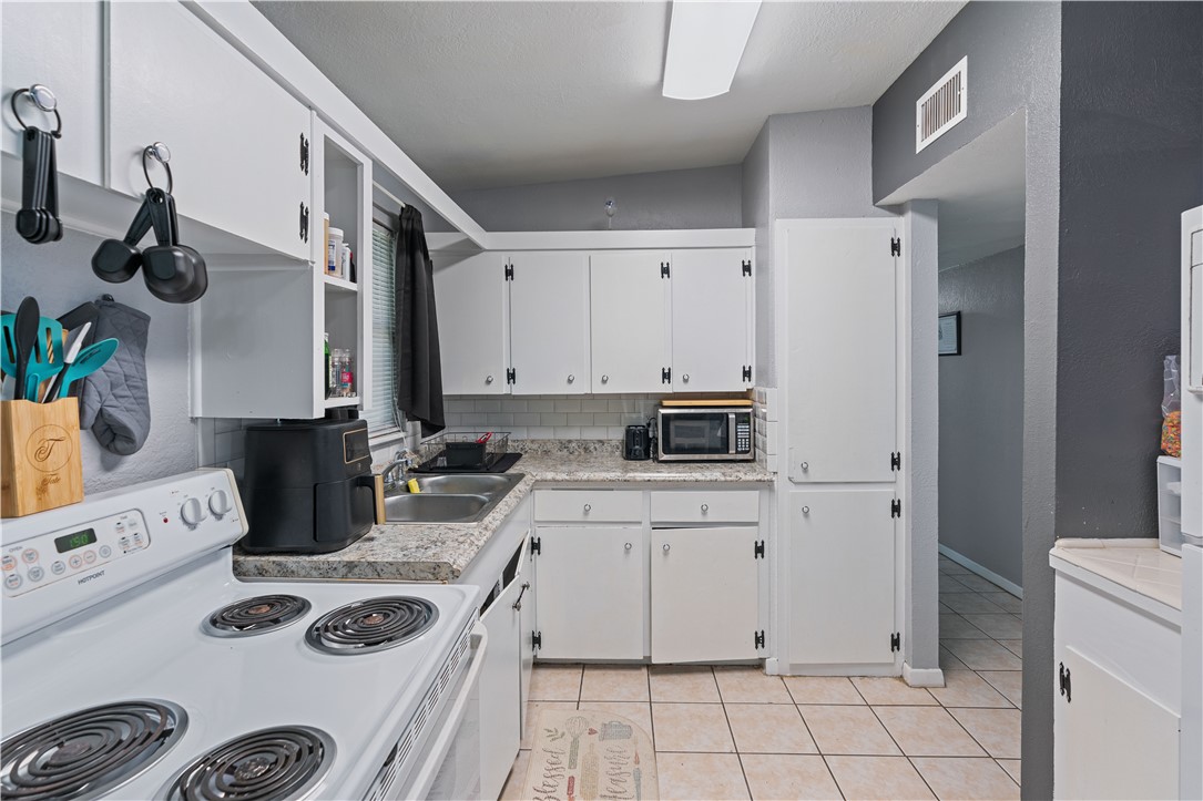 4846 Kasper Street Corpus Christi, TX 78415 - Photo 8 of 20 a kitchen with a sink dishwasher stove and white cabinets