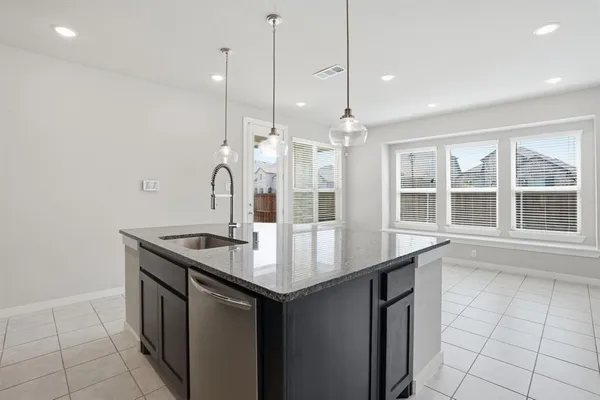 a kitchen with stainless steel appliances granite countertop a sink a stove and a wooden floor