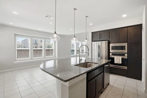 a kitchen with kitchen island a sink stainless steel appliances and a counter top space