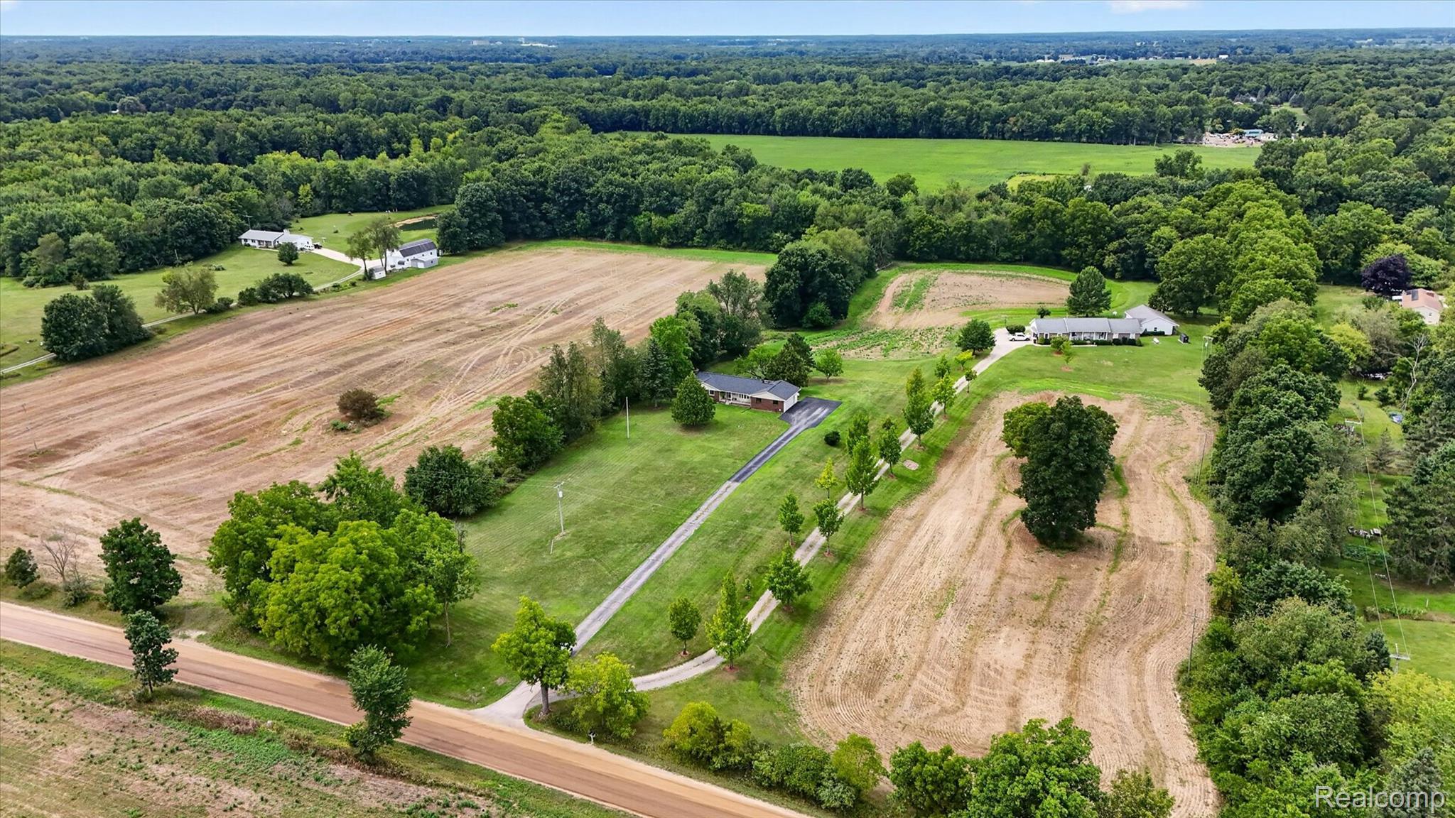 6895 Stow Road Fowlerville, MI 48836 - Photo 33 of 45 Expansive rural property featuring multiple residential structures, agricultural fields, a tree-lined driveway, and abundant mature trees