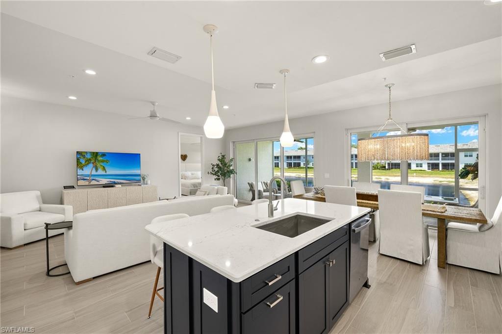 2647 Seychelles Circle, Unit 2203 Naples, FL 34112 - Photo 31 of 32 a kitchen with center island white cabinets and stainless steel appliances