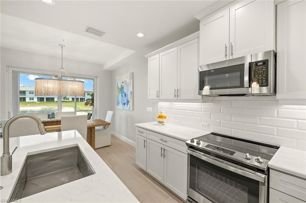 2647 Seychelles Circle, Unit 2203 Naples, FL 34112 - Photo 11 of 32 a kitchen with stainless steel appliances a stove a sink a microwave and cabinets
