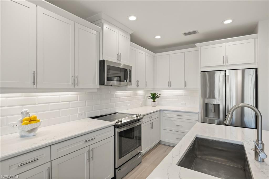 2647 Seychelles Circle, Unit 2203 Naples, FL 34112 - Photo 13 of 32 a kitchen with stainless steel appliances white cabinets and a sink