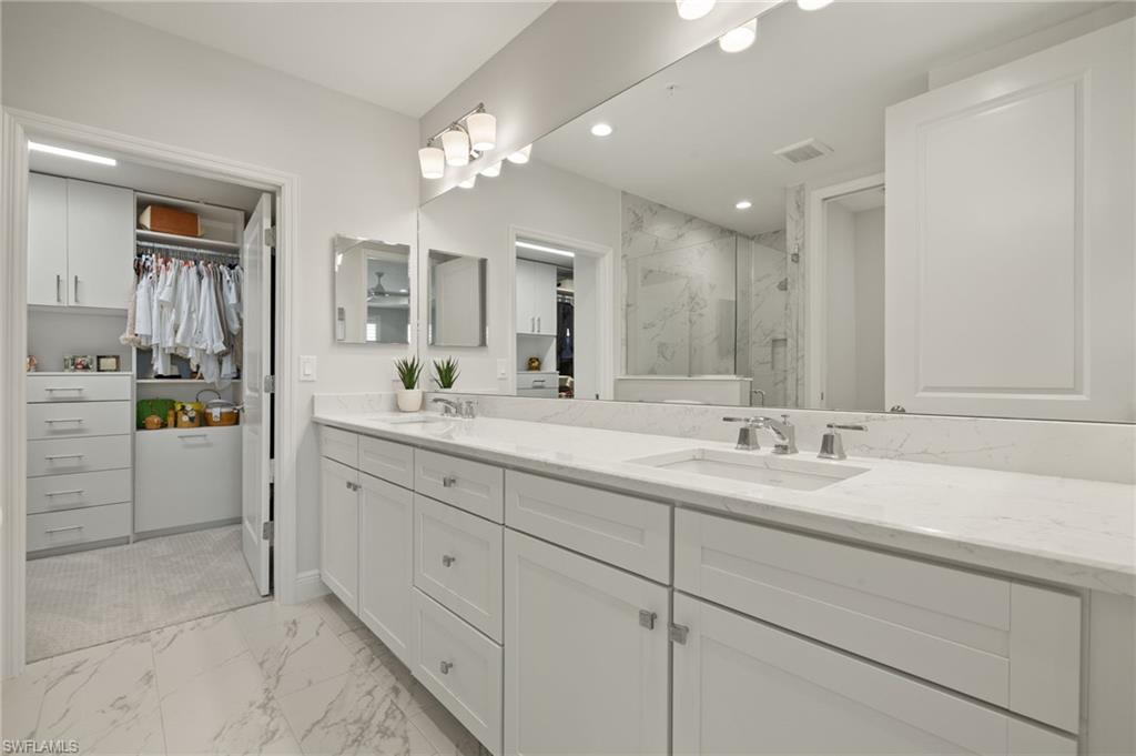 2647 Seychelles Circle, Unit 2203 Naples, FL 34112 - Photo 17 of 32 a bathroom with a double vanity sink a mirror and a shower
