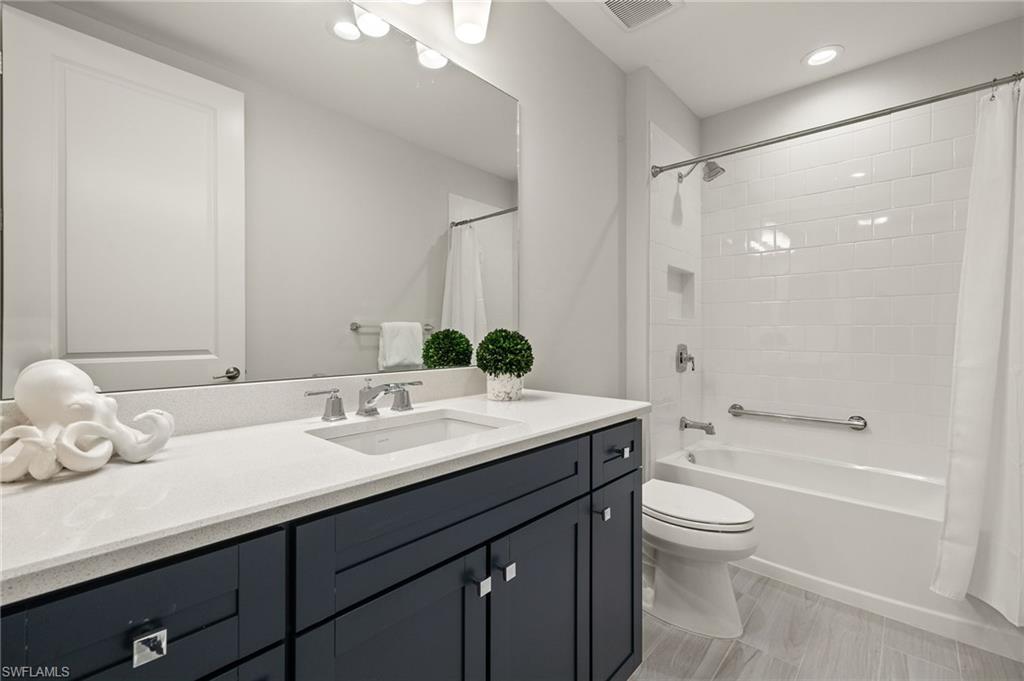 2647 Seychelles Circle, Unit 2203 Naples, FL 34112 - Photo 20 of 32 a bathroom with a granite countertop sink mirror vanity and toilet