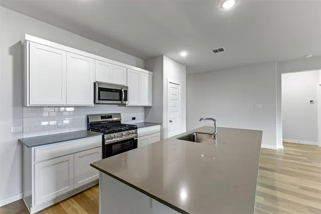 a kitchen with granite countertop a sink dishwasher stove and microwave with wooden floor