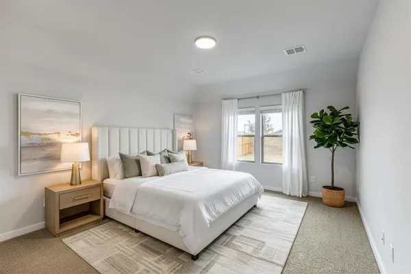 a bedroom with a large bed and a potted plant
