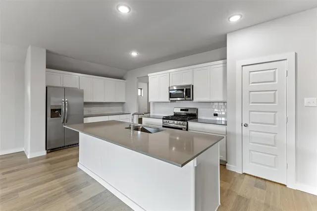 a kitchen with a refrigerator a stove top oven and wooden floor