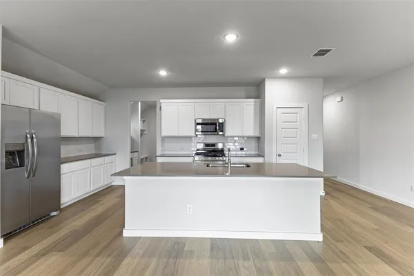 a large kitchen with stainless steel appliances a large counter top a stove and a refrigerator