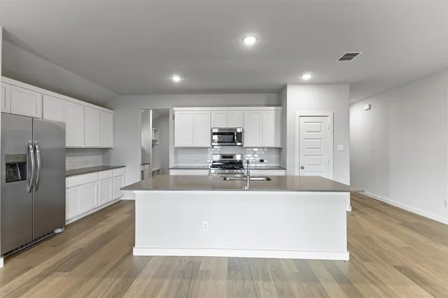 a large kitchen with stainless steel appliances a large counter top a stove and a refrigerator