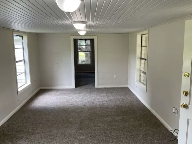 en empty room with windows and chandelier fan