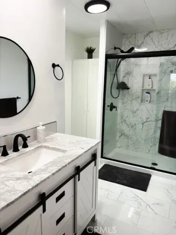 a bathroom with a granite countertop sink a mirror and shower