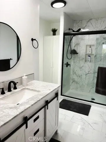a bathroom with a granite countertop sink a mirror and shower