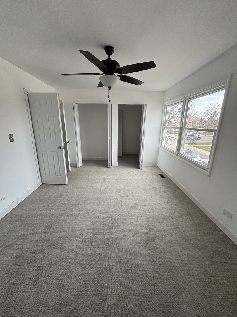 1707 Queensbury Circle Hoffman Estates, IL 60169 - Photo 8 of 10 an empty room with windows and ceiling fan