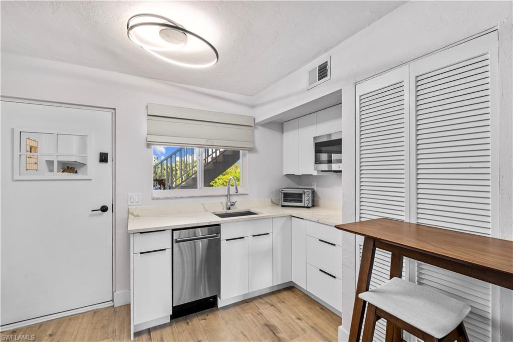 377 Vanderbilt Beach Road, Unit 102 Naples, FL 34108 - Photo 4 of 19 a kitchen with a sink cabinets and wooden floor
