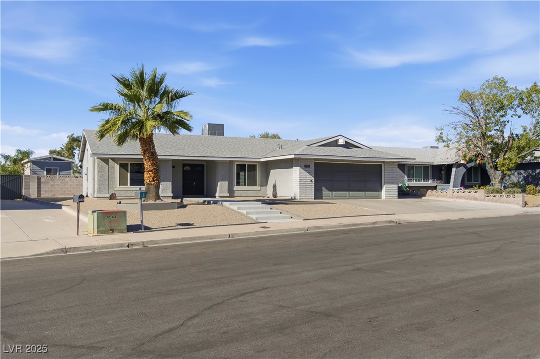 Single story home with driveway, a garage, covered porch, and a shingled roof