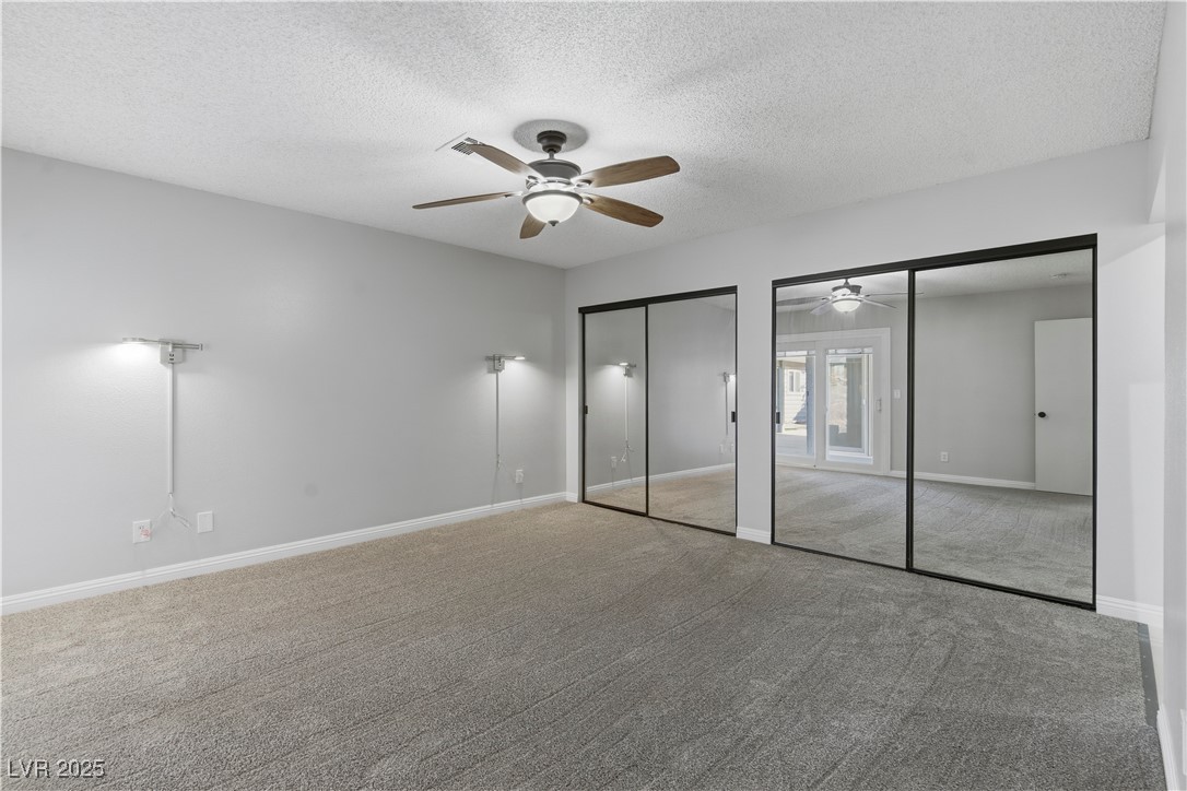 782 Darlene Way Boulder City, NV 89005 - Photo 17 of 39 Unfurnished bedroom with two closets, a textured ceiling, carpet flooring, and ceiling fan