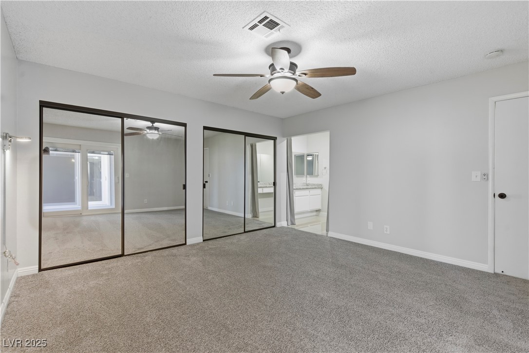 782 Darlene Way Boulder City, NV 89005 - Photo 18 of 39 Unfurnished bedroom with multiple closets, carpet floors, a textured ceiling, connected bathroom, and a ceiling fan