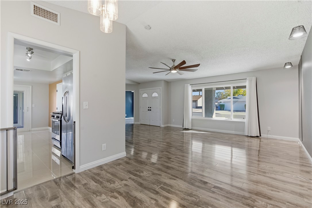 782 Darlene Way Boulder City, NV 89005 - Photo 8 of 39 Unfurnished living room featuring ceiling fan, a textured ceiling, and light wood-style floors