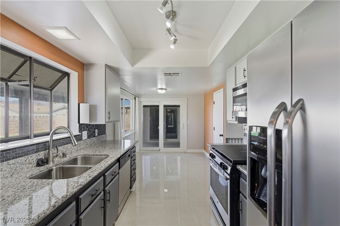 782 Darlene Way Boulder City, NV 89005 - Photo 10 of 39 Kitchen featuring stainless steel appliances, light stone countertops, rail lighting, a raised ceiling, and light tile patterned flooring