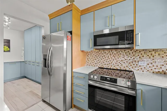 a kitchen with stainless steel appliances kitchen island granite countertop a refrigerator and a stove top oven