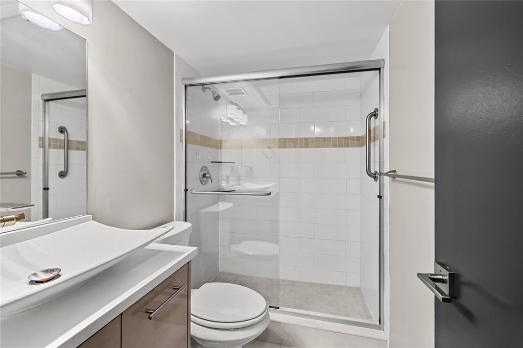 808 Southeast 7th Street, Unit 105B Deerfield Beach, FL 33441 - Photo 27 of 43 a bathroom with a sink a mirror toilet and shower